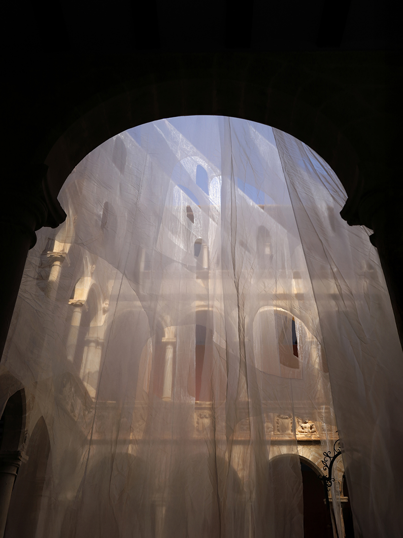 translucent organza curtains float within renaissance arched courtyard in spain