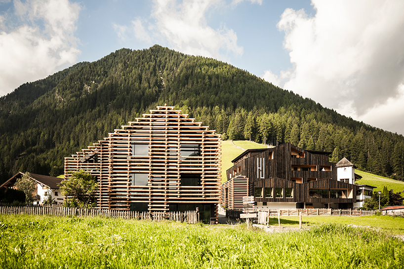 DEAR studio adapts old hay barns into modern larch log-clad hotel in italian alps