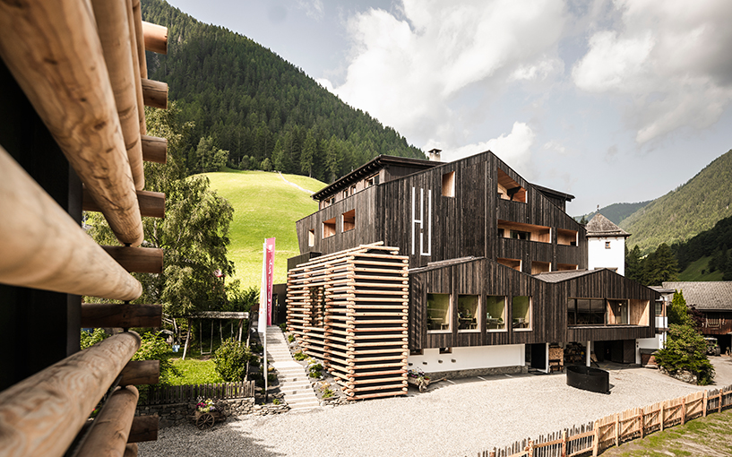 DEAR studio adapts old hay barns into modern larch log-clad hotel in italian alps