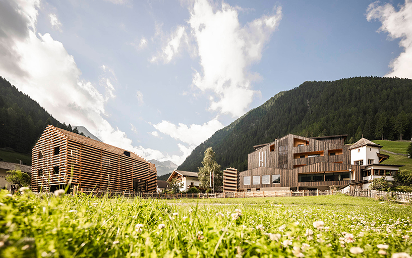 DEAR studio adapts old hay barns into modern larch log-clad hotel in italian alps