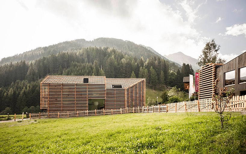 DEAR studio adapts old hay barns into modern larch log-clad hotel in italian alps