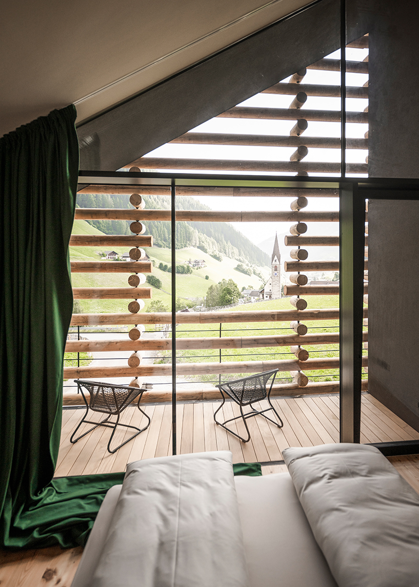 DEAR studio adapts old hay barns into modern larch log-clad hotel in italian alps