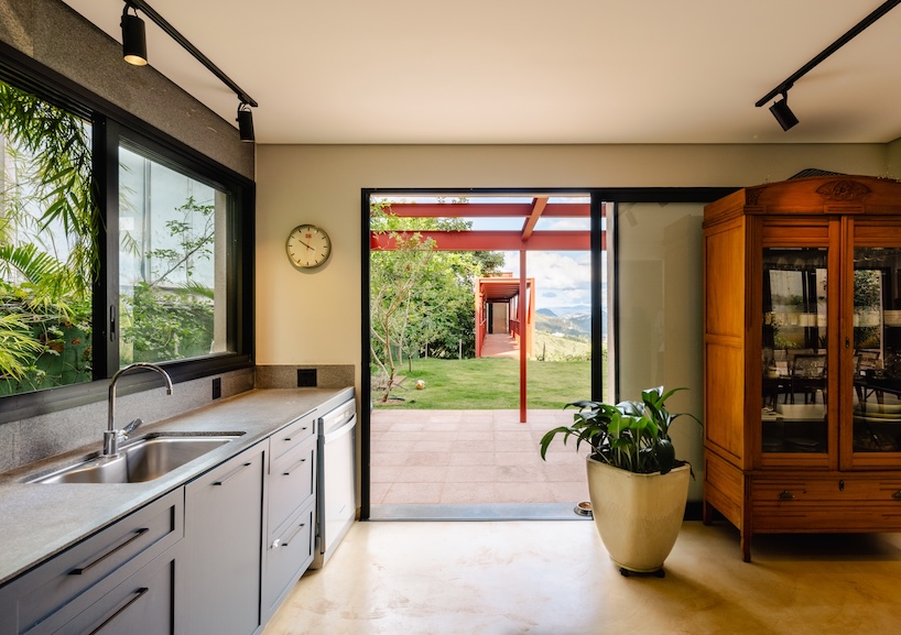 red elevated metal walkway extends casa castela across steep brazilian slope - 5
