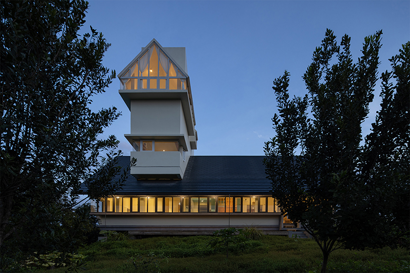 white tower pierces through the gable roof of silkworm house in vietnam