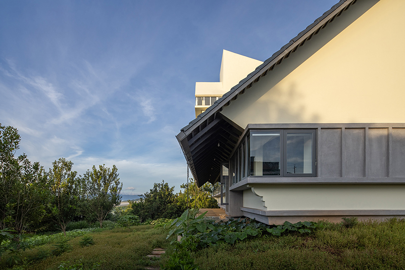 white tower pierces through the gable roof of silkworm house in vietnam