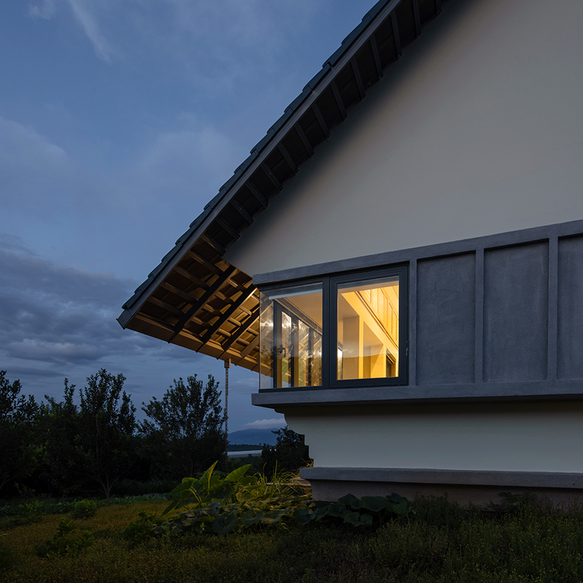 white tower pierces through the gable roof of silkworm house in vietnam