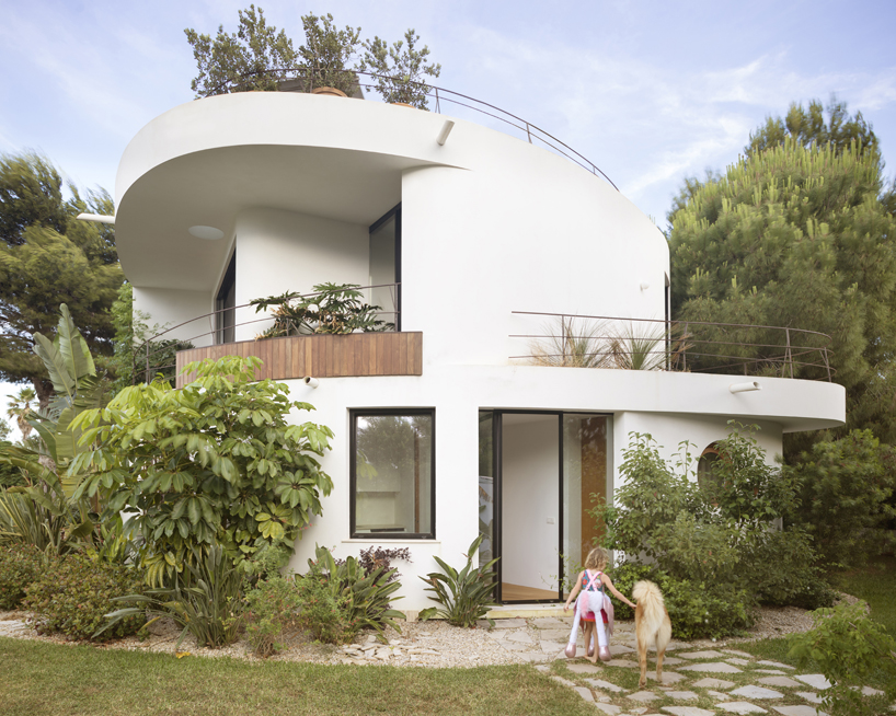 curved white volumes and verdant surroundings define house in les rotes, spain