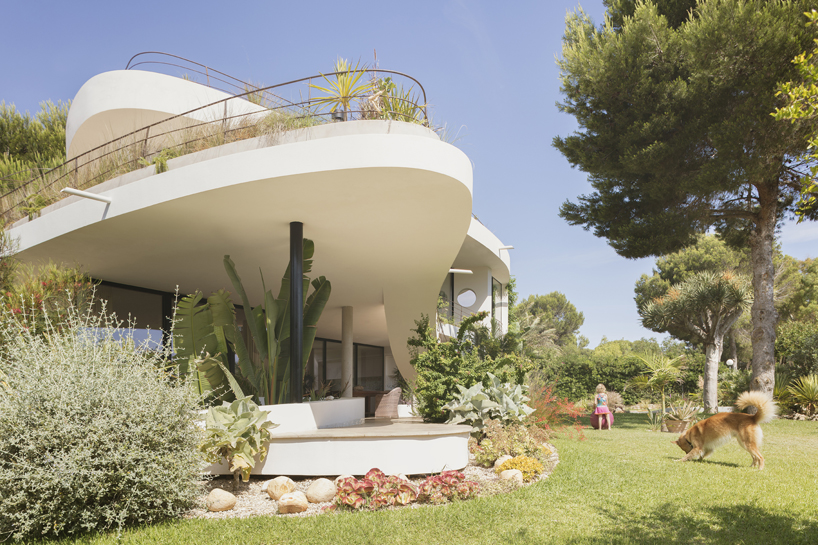 curved white volumes and verdant surroundings define house in les rotes, spain