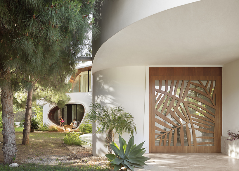 curved white volumes and verdant surroundings define house in les rotes, spain