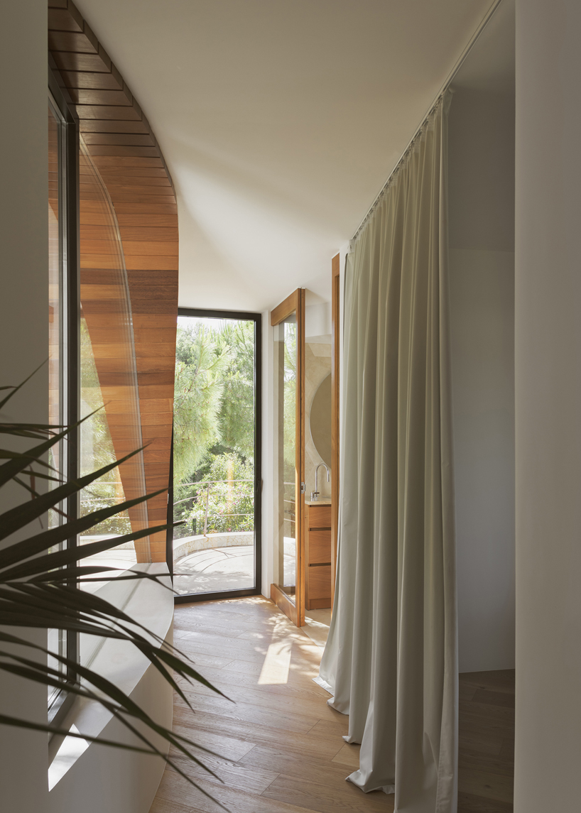 curved white volumes and verdant surroundings define house in les rotes, spain