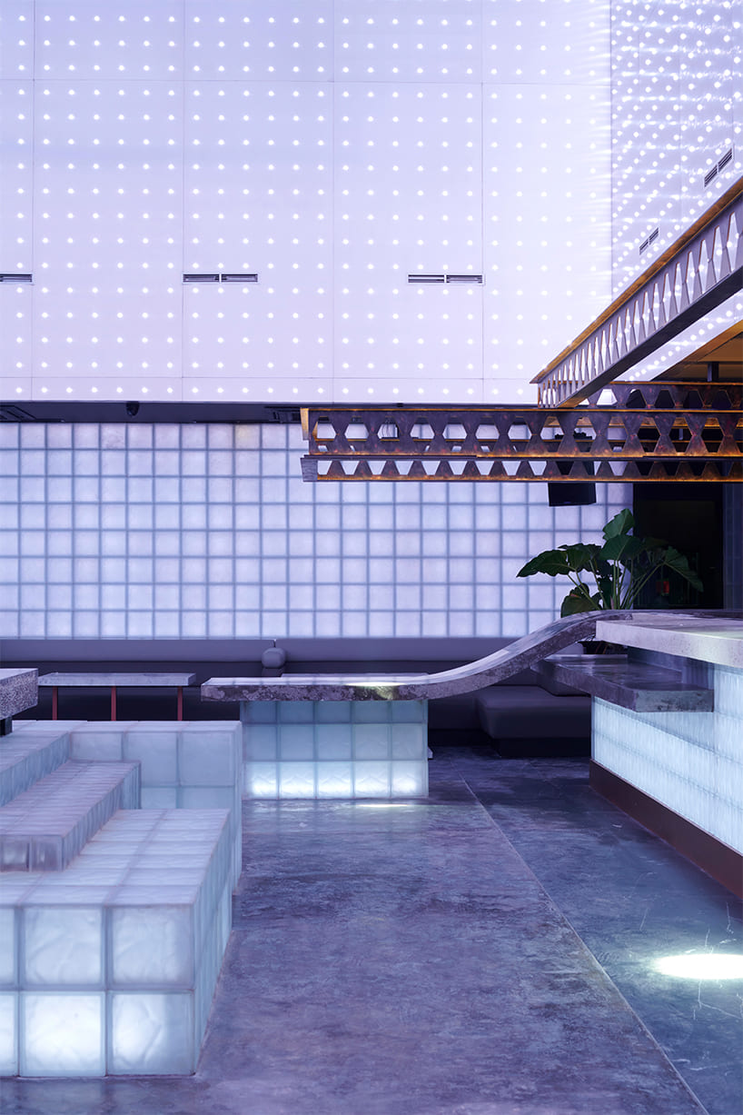 neon lights permeate glass block walls of renovated hidden basement bar in indonesia