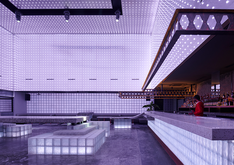 neon lights permeate glass block walls of renovated hidden basement bar in indonesia