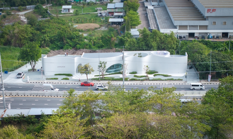 uncloud coffee's arching white structure integrates smoothly into its surroundings in thailand