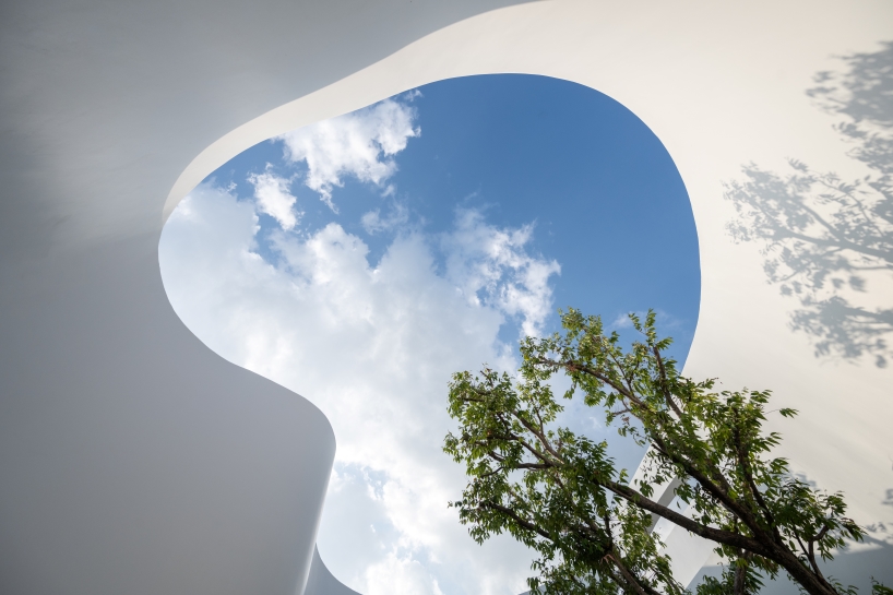 uncloud coffee's arching white structure integrates smoothly into its surroundings in thailand