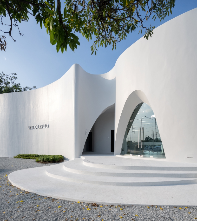 uncloud coffee's arching white structure integrates smoothly into its surroundings in thailand
