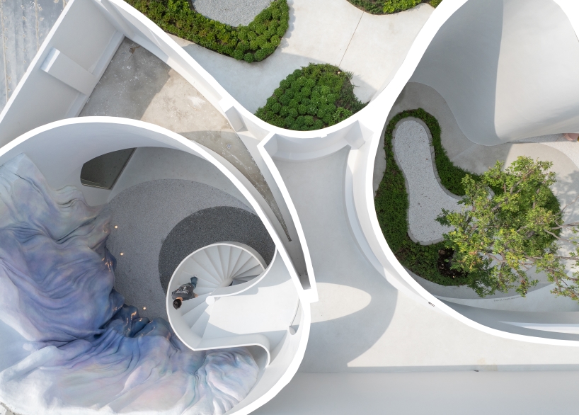 uncloud coffee's arching white structure integrates smoothly into its surroundings in thailand