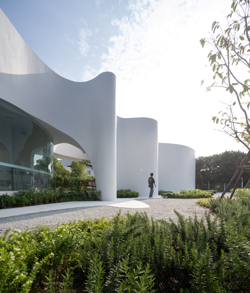 uncloud coffee's arching white structure integrates smoothly into its surroundings in thailand