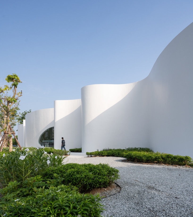 uncloud coffee's arching white structure integrates smoothly into its surroundings in thailand