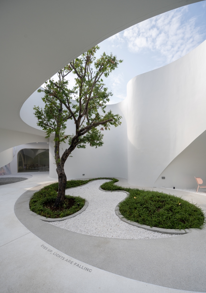 uncloud coffee's arching white structure integrates smoothly into its surroundings in thailand
