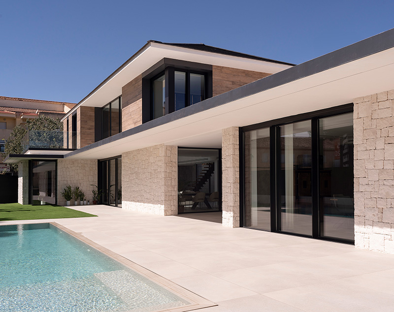 Two-story home clad in distinctive Spanish black tiles and quarried stone