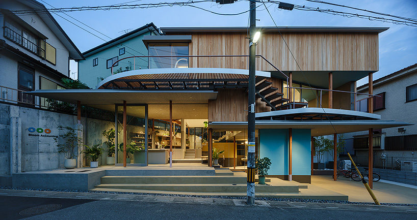 fragmented timber blue box office stands on sloping terrain in japan