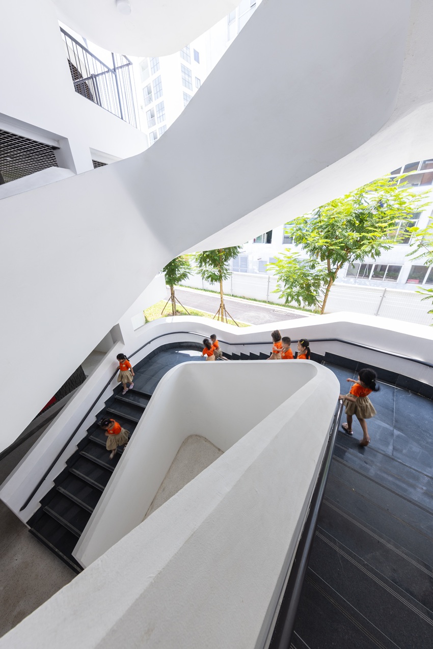 elliptical classroom volumes and colorful louvers shape courtyard kindergarten in hanoi - 9