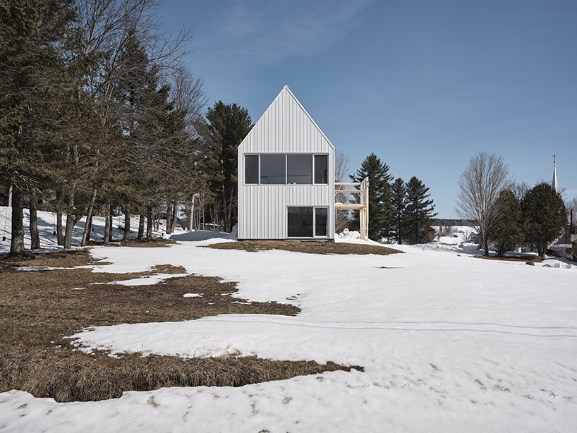 white cladding envelops la musette gabled village hut in canadian hillside