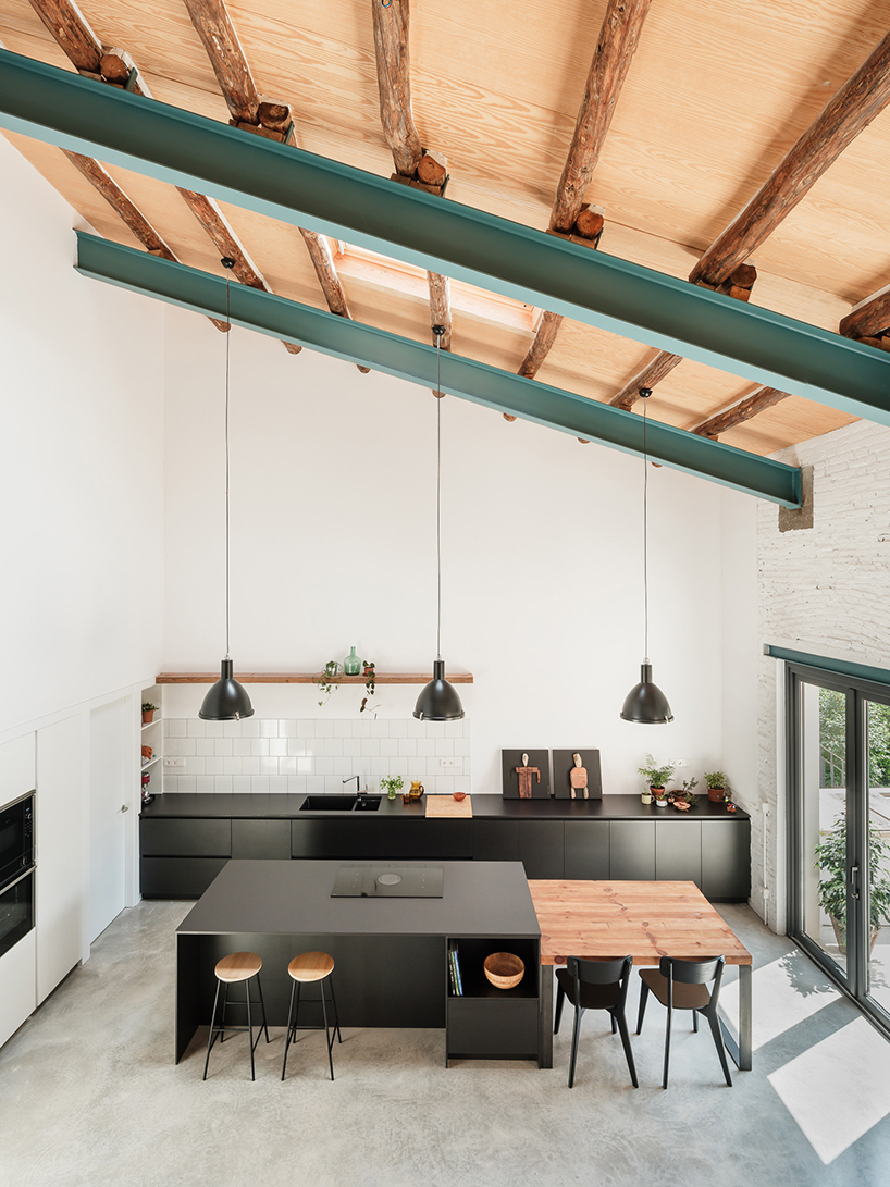 repurposed wood shapes up the roof and furniture of converted warehouse in spain