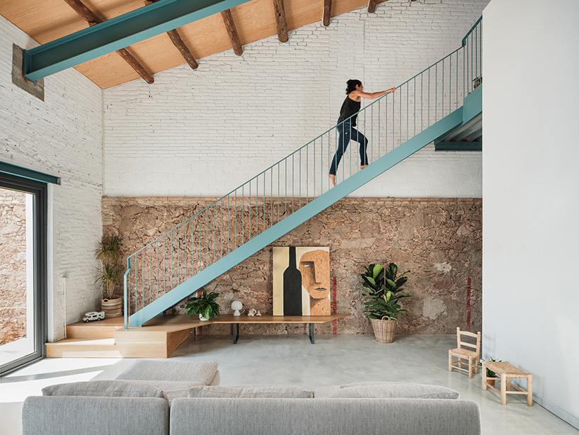 repurposed wood shapes up the roof and furniture of converted warehouse in spain