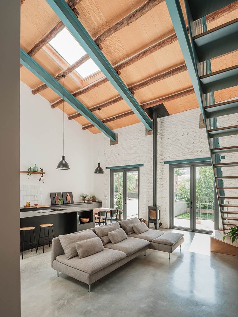 repurposed wood shapes up the roof and furniture of converted warehouse in spain