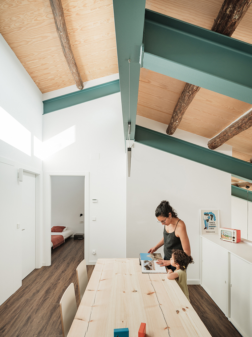 repurposed wood shapes up the roof and furniture of converted warehouse in spain