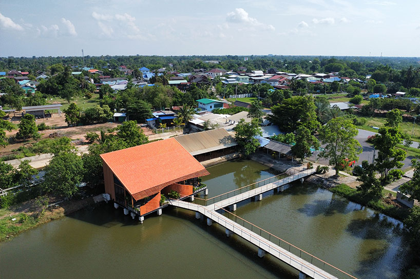 clad in terracotta tiles, morjor café floats above water pond in thailand