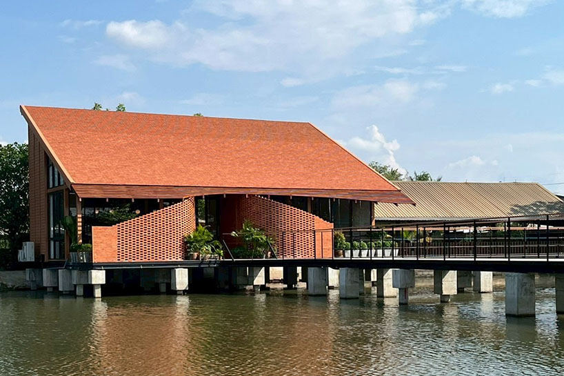 clad in terracotta tiles, morjor café floats above water pond in thailand
