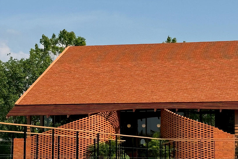 clad in terracotta tiles, morjor café floats above water pond in thailand