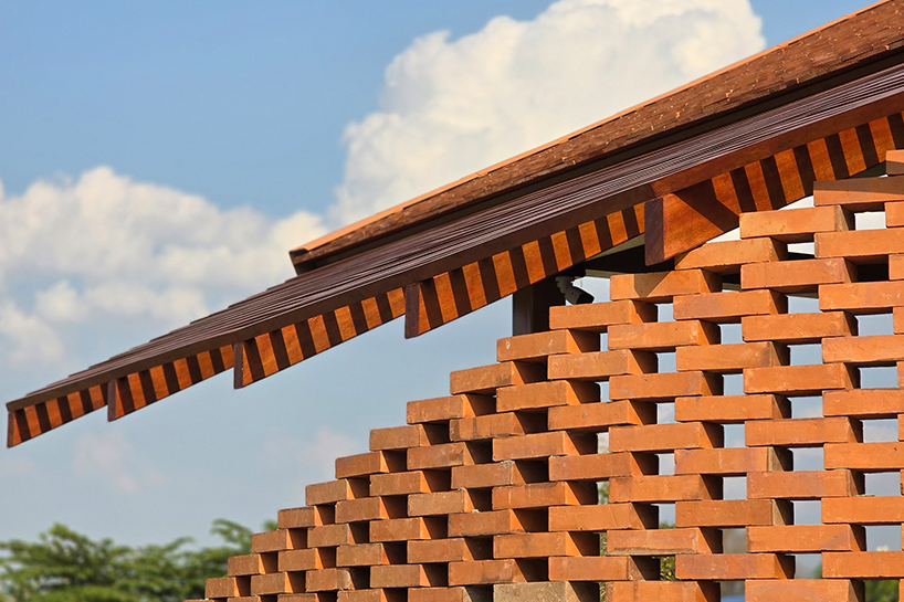 clad in terracotta tiles, morjor café floats above water pond in thailand