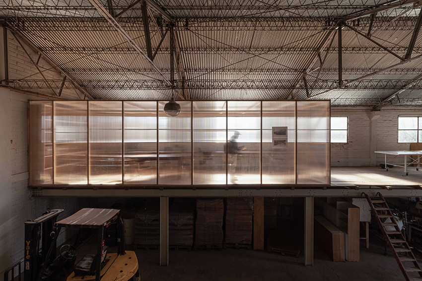 les panneaux en polycarbonate reflètent la lumière dans un atelier industriel minimaliste en Argentine