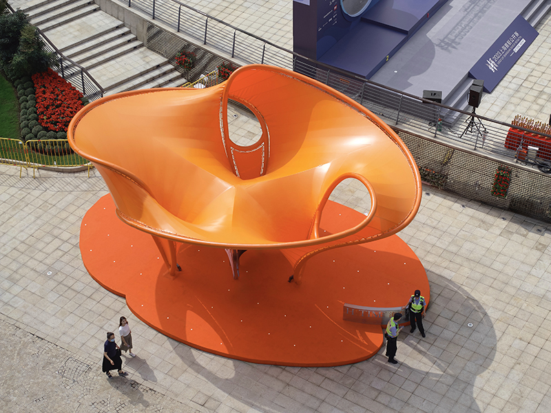 orange tensile membrane attaches to curved steel pipes shaping eddy pavilion in shanghai