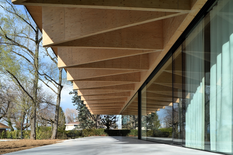Paneles de madera tipo origami se despliegan sobre la casa Bachholz en el lago de Ginebra
