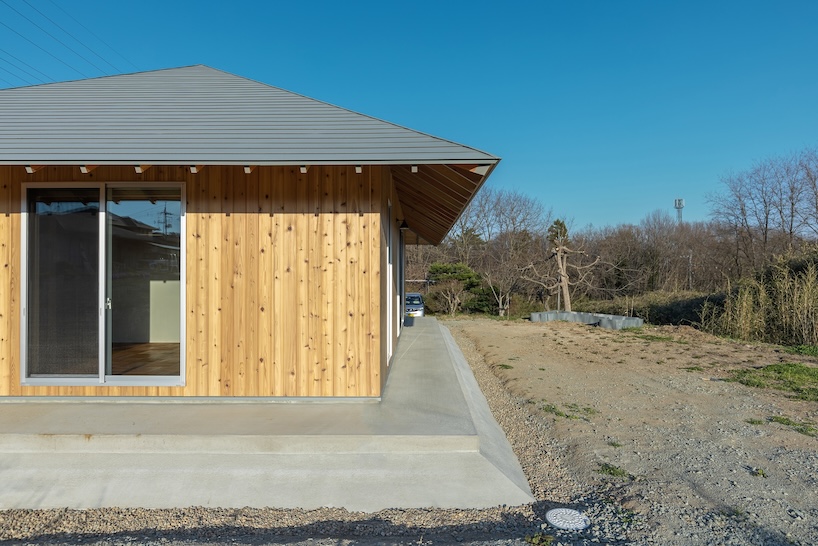 une maison en bois par architrip s'étend de manière fluide dans le jardin environnant au Japon