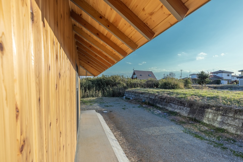 une maison en bois par architrip s'étend de manière fluide dans le jardin environnant au Japon