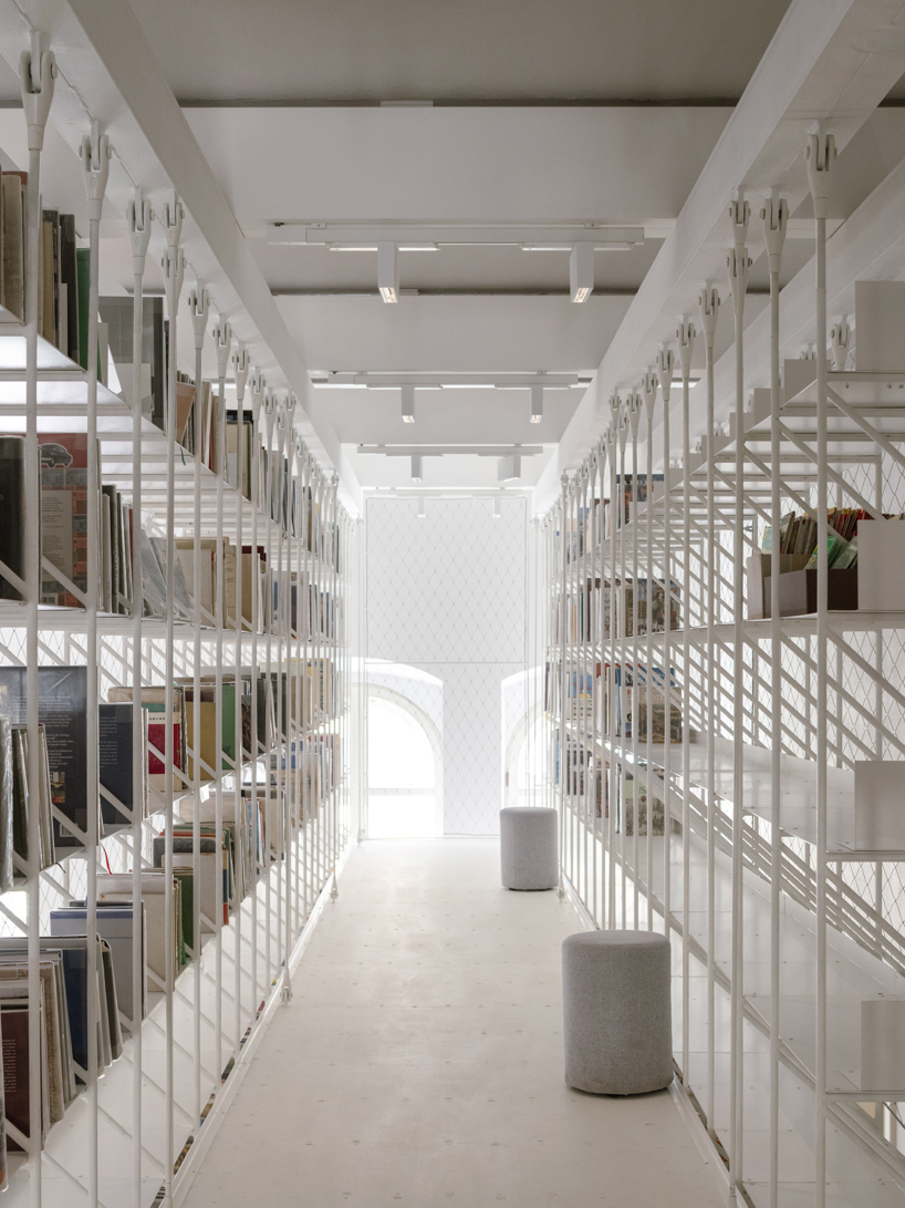 suspended steel shelving forms permeable curtain within revitalized historic slovak library