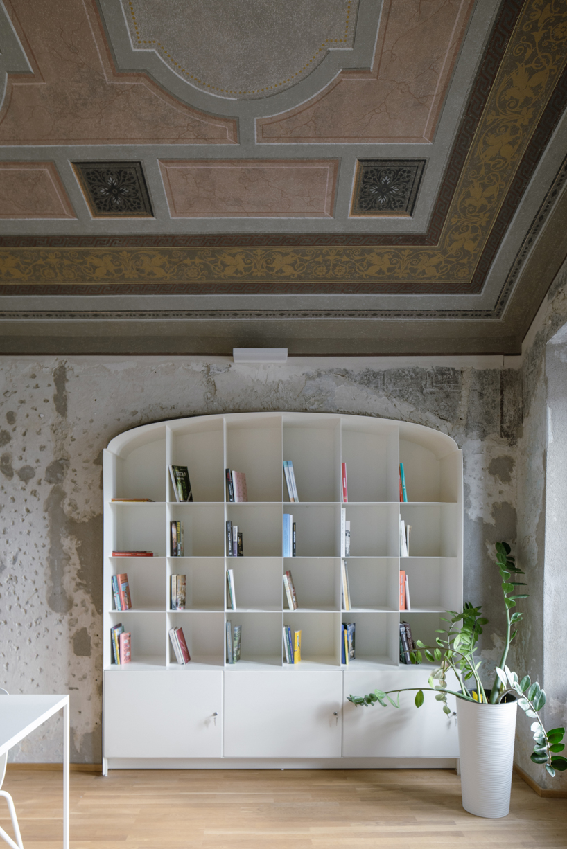 suspended steel shelving forms permeable curtain within revitalized historic slovak library