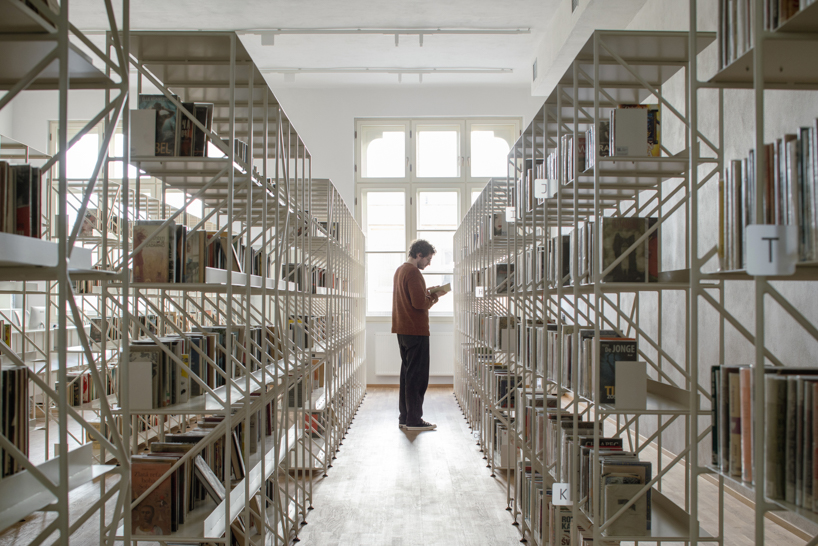 suspended steel shelving forms permeable curtain within revitalized historic slovak library