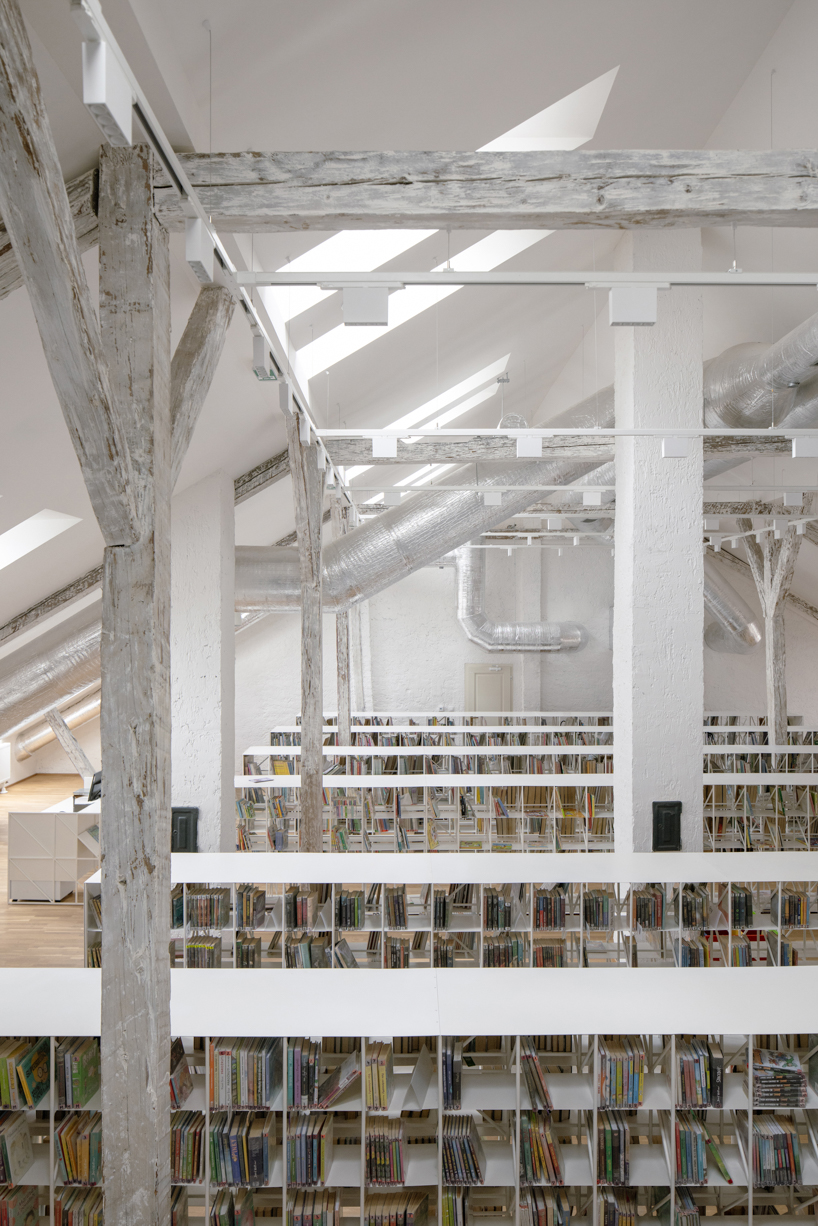 suspended steel shelving forms permeable curtain within revitalized historic slovak library