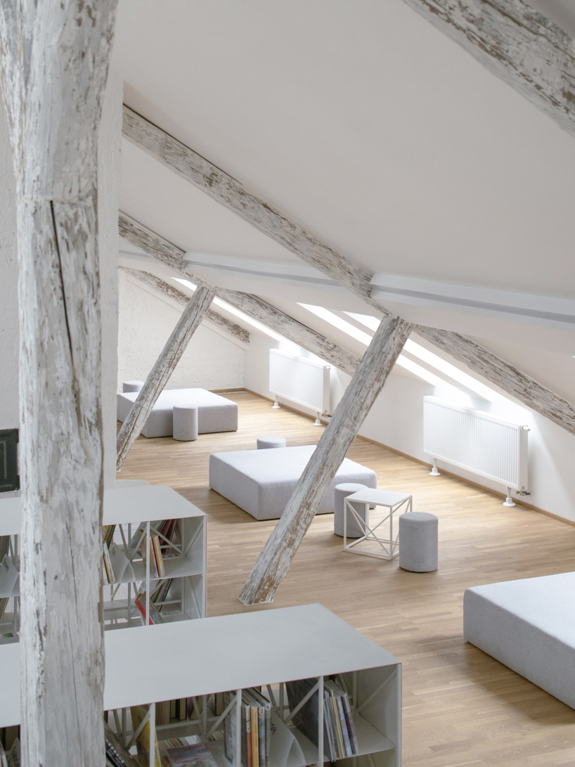suspended steel shelving forms permeable curtain within revitalized historic slovak library