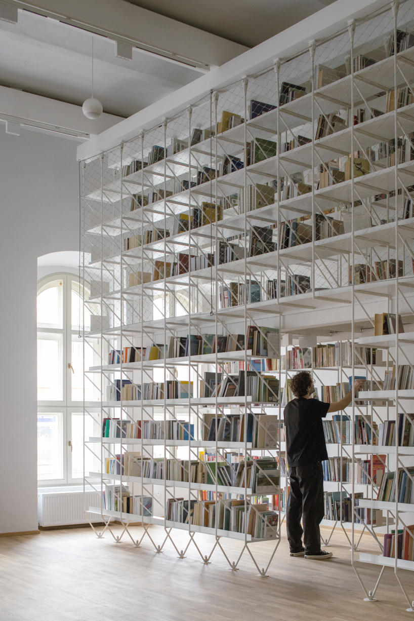 suspended steel shelving forms permeable curtain within revitalized historic slovak library
