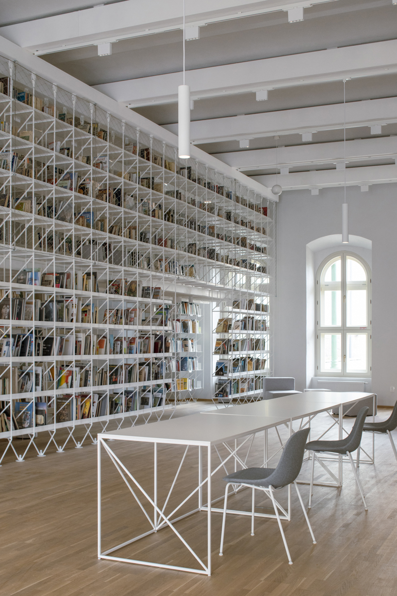 suspended steel shelving forms permeable curtain within revitalized historic slovak library