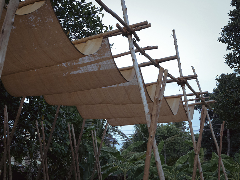 tensile fabric weaves through studio terratects' wooden trestle pavilion in india