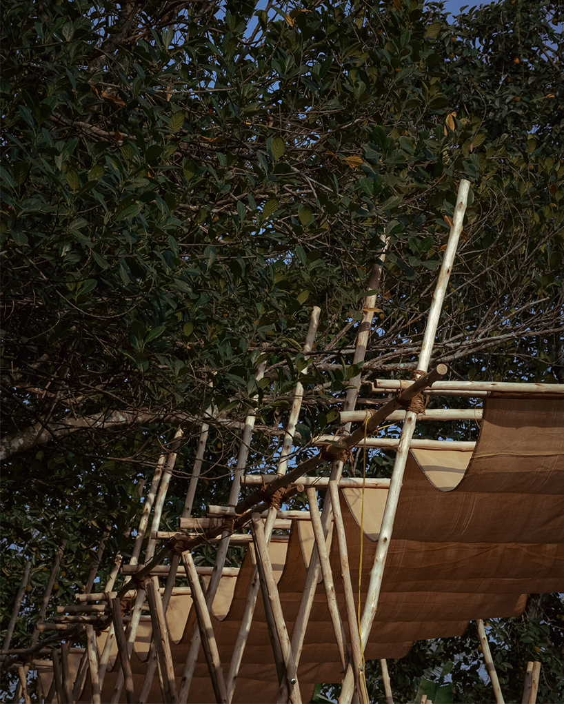 tensile fabric weaves through studio terratects' wooden trestle pavilion in india