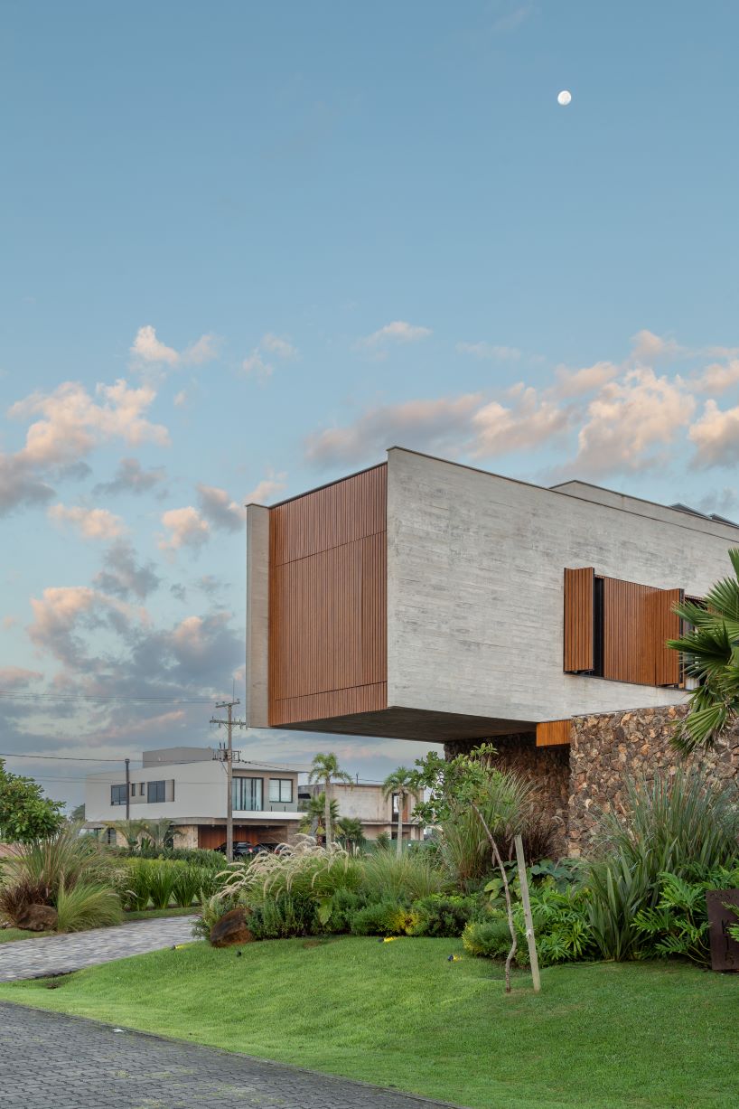 Oficina conceito arquitetura's cantilevered house rests on a stone volume in Brazil